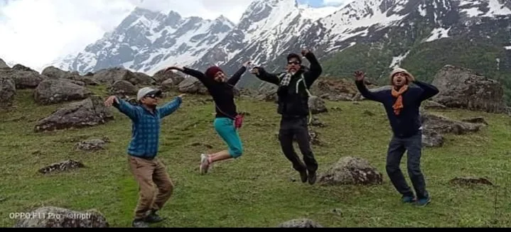 Trekkers celebrating in the meadow below the snow peaks